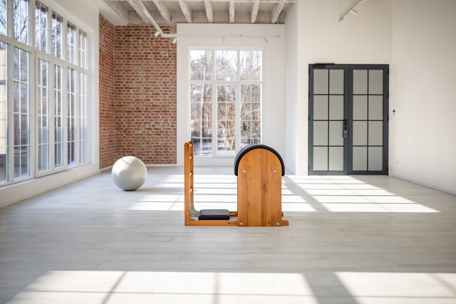 Young woman practicing Pilates indoors with specialized equipment in a spacious, well-lit studio for a healthy lifestyle